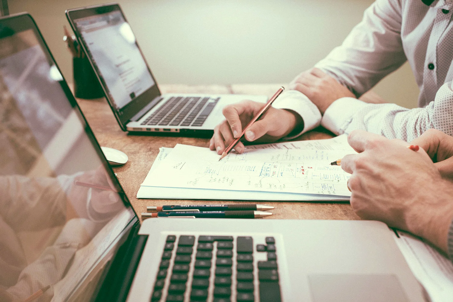 Two people planning a schedule on paper next to open laptops